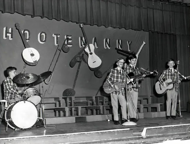 black and white photo of kids playing guitar and drums on stage